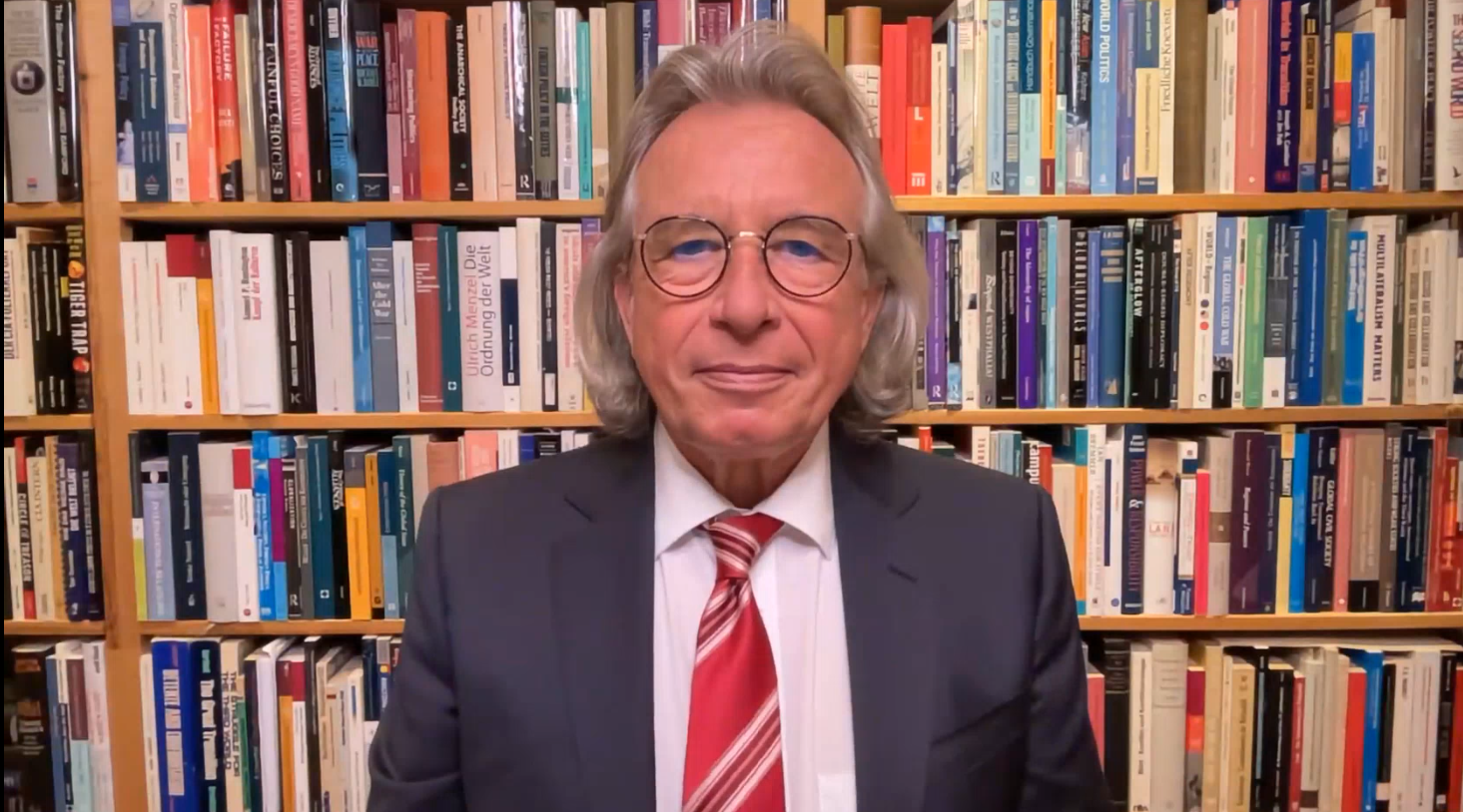 Ein Mann mit Brille, Anzug, Krawatte und längerem grauen Haar vor einer Bücherwand: Es ist Thomas Jäger, Professor für Internationale Politik und Außenpolitik