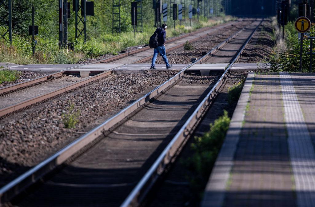06.08.2025, Mecklenburg-Vorpommern, Schwerin: Ein Reisender geht über die Gleise der Deutschen Bahn zur Haltestelle der Ersatzbusse. Wegen Bauarbeiten ist die zweigleisige Schienenstrecke gesperrt und Busse ersetzen in den nächsten neuen Monaten die Personenzüge auf der Strecke zwischen Berlin und Hamburg. Mit 230 Zügen und bis zu 30.000 Fahrgästen pro Tag ist die rund 280 Kilometer lange Strecke eine der wichtigsten Direktverbindungen der Bahn. In Bayern beginnen die Korridorsanierungen im nächsten Jahr mit der Strecke Regensburg - Nürnberg
