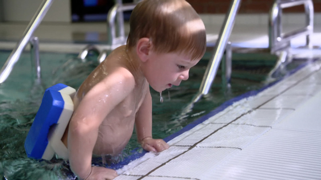 Kind mit Schwimmgürtel im Becken