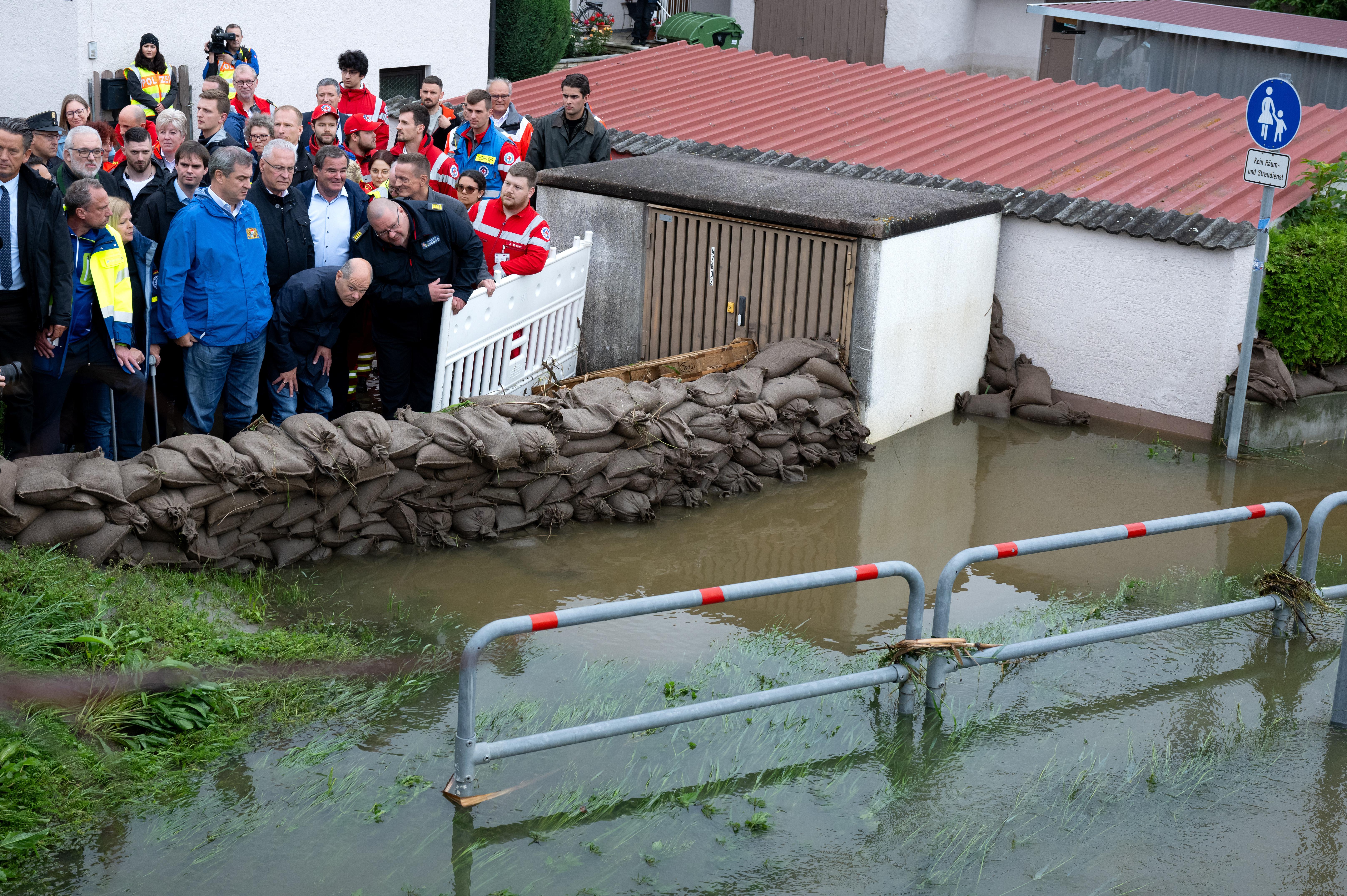 Bundeskanzler Olaf Scholz und Ministerpräsident Markus Söder stehen hinter eine Barriere aus Sandsäcken in Reichertshofen.