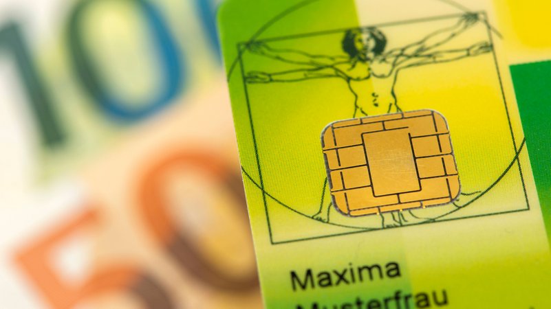 Eine Gesundheitskarte liegt über Euro Banknoten. | Bild: picture alliance / SZ Photo | Wolfgang Filser Eine Gesundheitskarte liegt über Euro Banknoten.
