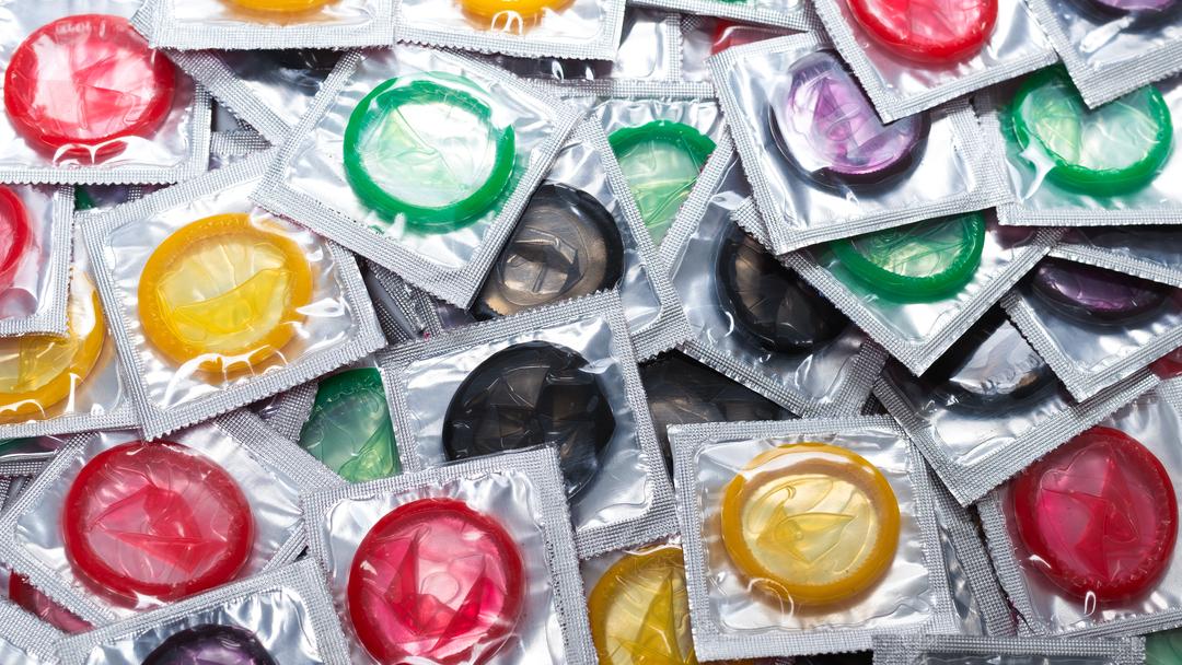 Viele bunte, verpackte Kondome auf einem Haufen.