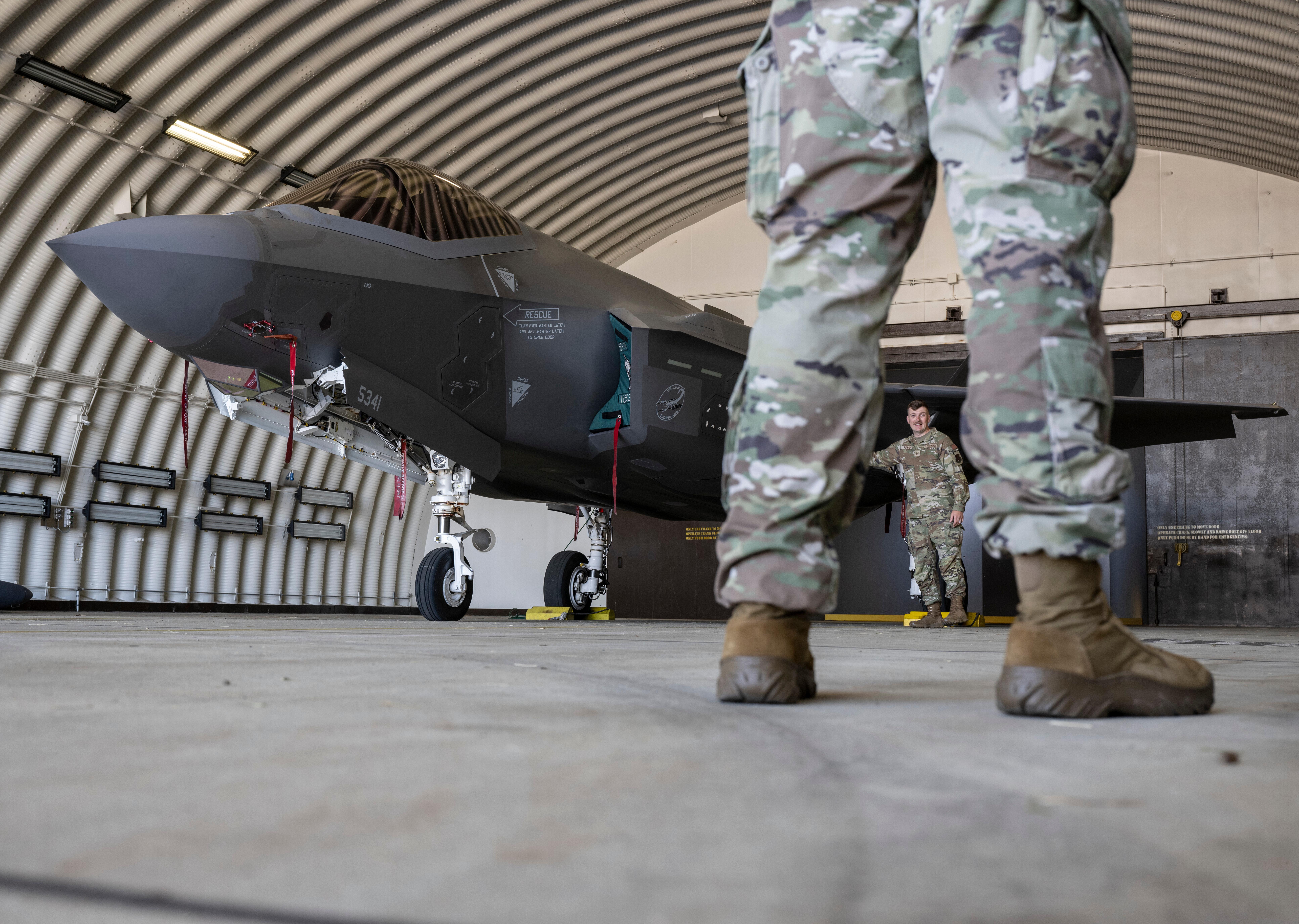 (symbolbild) Ein Kampfflugzeug vom Typ F-35 der US Air Force und US-Soldaten stehen in einem Hangar auf der US-Air Base Spangdahlem in Rheinland-Pfalz (Archivbild vom 14.06.2023).