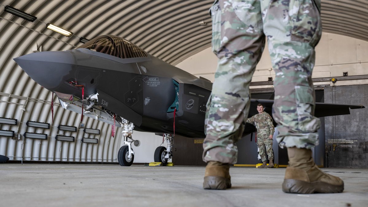 (symbolbild) Ein Kampfflugzeug vom Typ F-35 der US Air Force und US-Soldaten stehen in einem Hangar auf der US-Air Base Spangdahlem in Rheinland-Pfalz (Archivbild vom 14.06.2023).