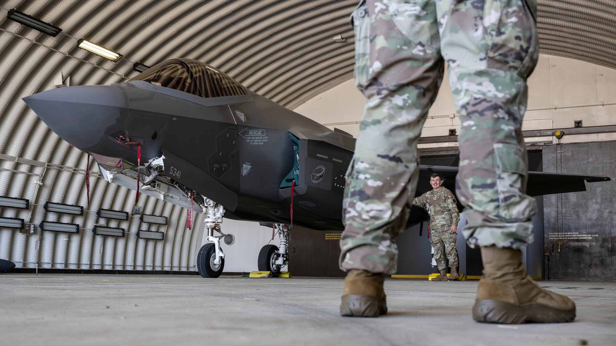 (symbolbild) Ein Kampfflugzeug vom Typ F-35 der US Air Force und US-Soldaten stehen in einem Hangar auf der US-Air Base Spangdahlem in Rheinland-Pfalz (Archivbild vom 14.06.2023).