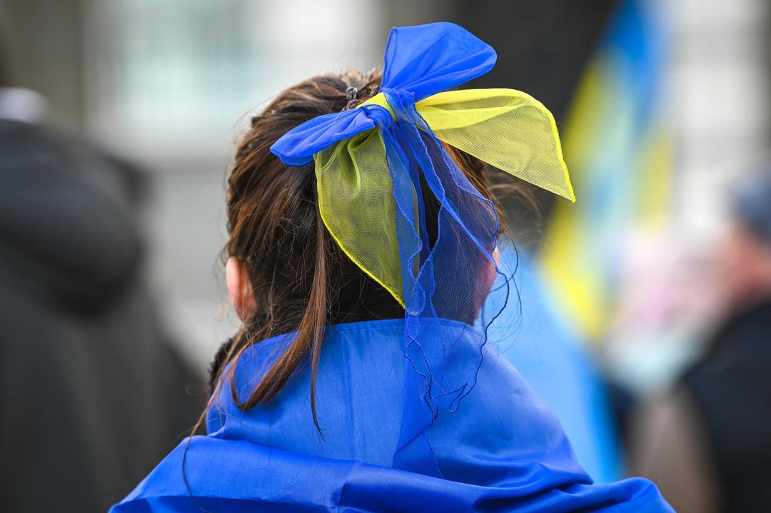 Eine Teilnehmerin der Demonstration "Das Licht wird die Dunkelheit besiegen" vom 24. Februar 2024 in Halle hat eine Schleife in den Nationalfarben der Ukraine in den Haaren.