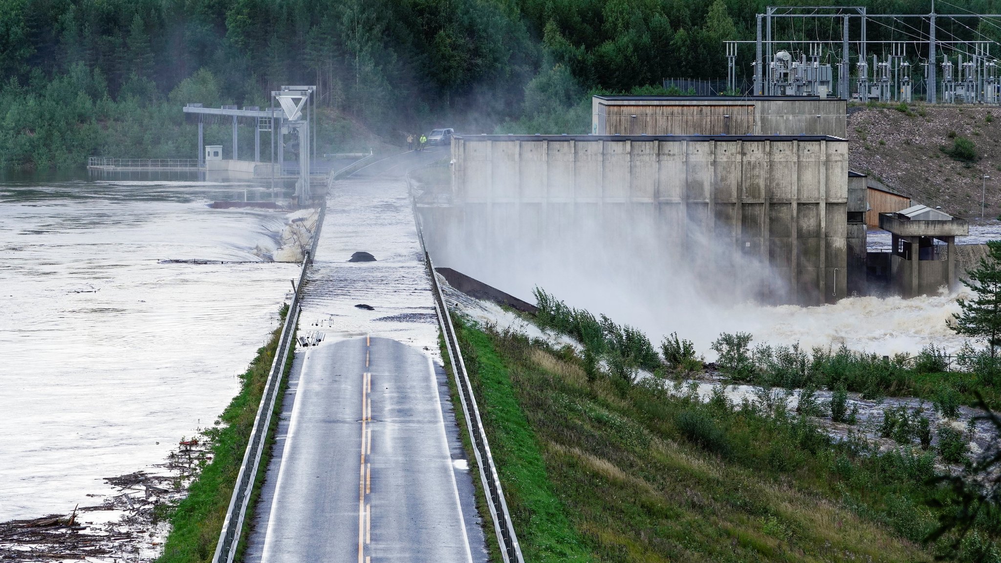 Zu sehen ist, wie riesige Mengen Wasser nach dem Teilbruch des Dammes die Dammkrone unterspülen.