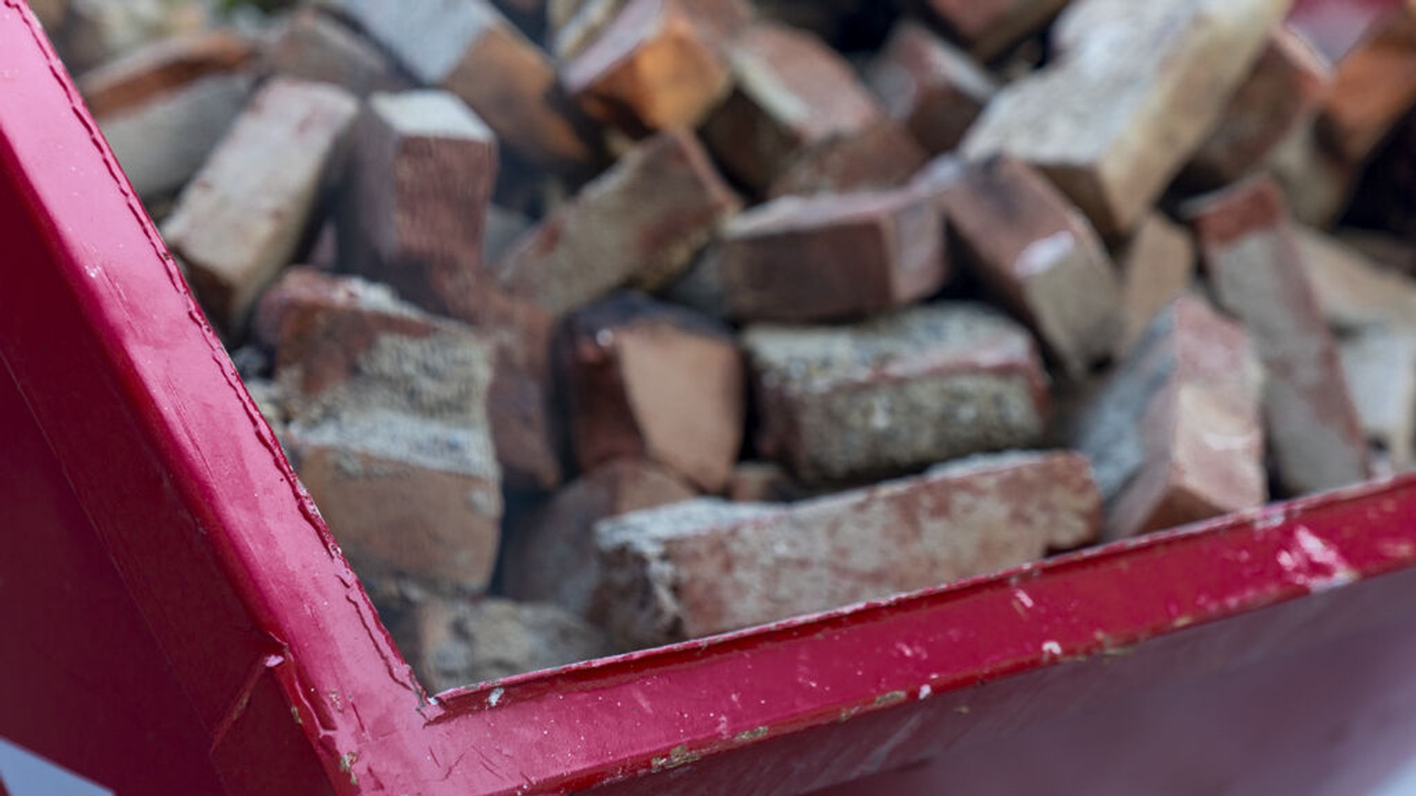 Ein roter Container gefüllt mit Bauschutt.