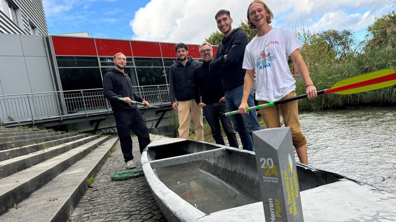 Die Studenten der Technischen Hochschule Augsburg stehen am Wasser und zeigen ihr Kanu aus Beton. | Bild: BR/René Kirsch Die Studenten der Technischen Hochschule Augsburg stehen am Wasser und zeigen ihr Kanu aus Beton.