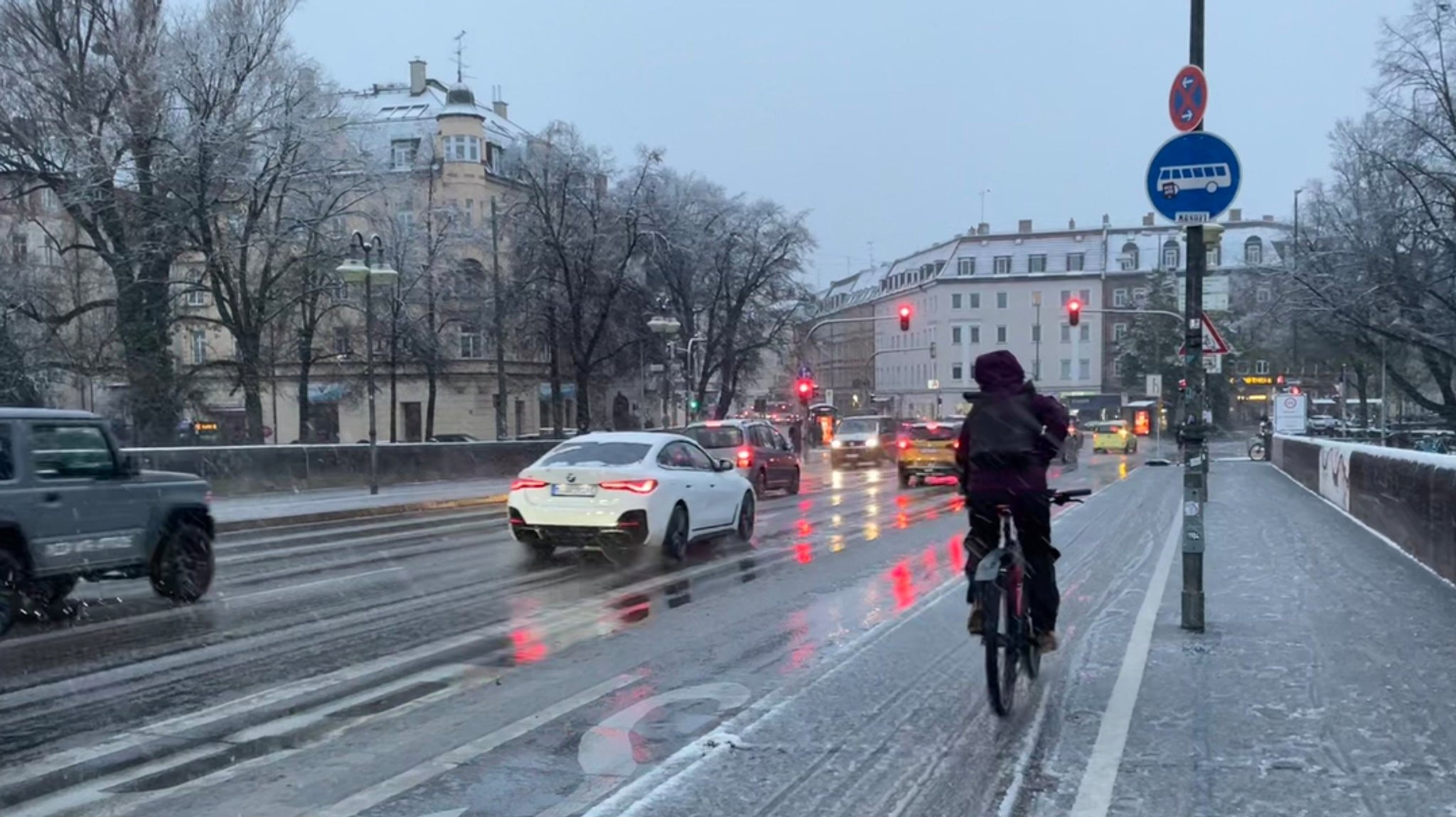 Autos und ein Radfahrer sind am Morgen (20.11.24) bei Schneematsch ins Münchner Stadtzentrum unterwegs