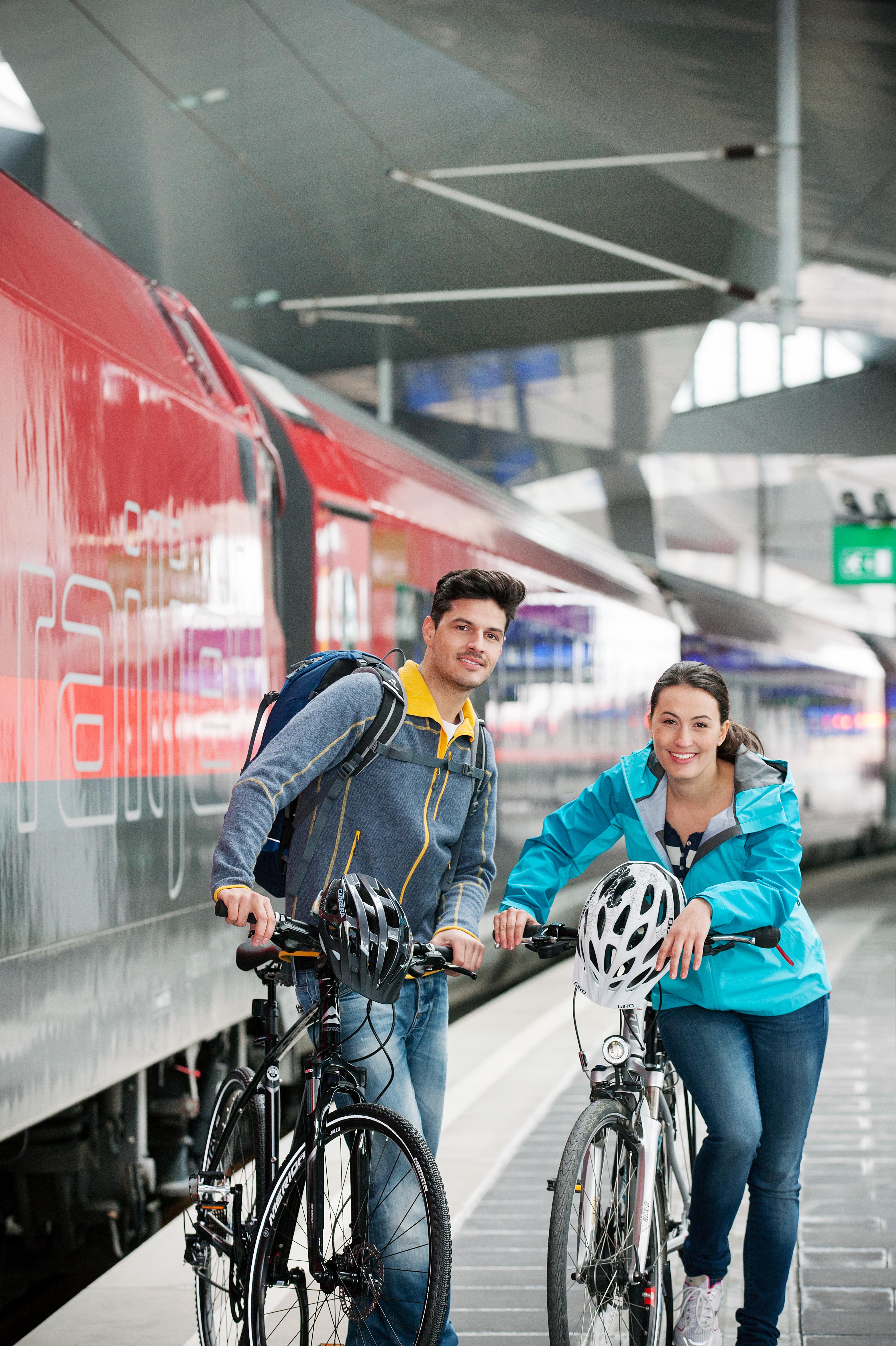 Ein Mann und eine Frau mit Fahrrädern vor einem Zug