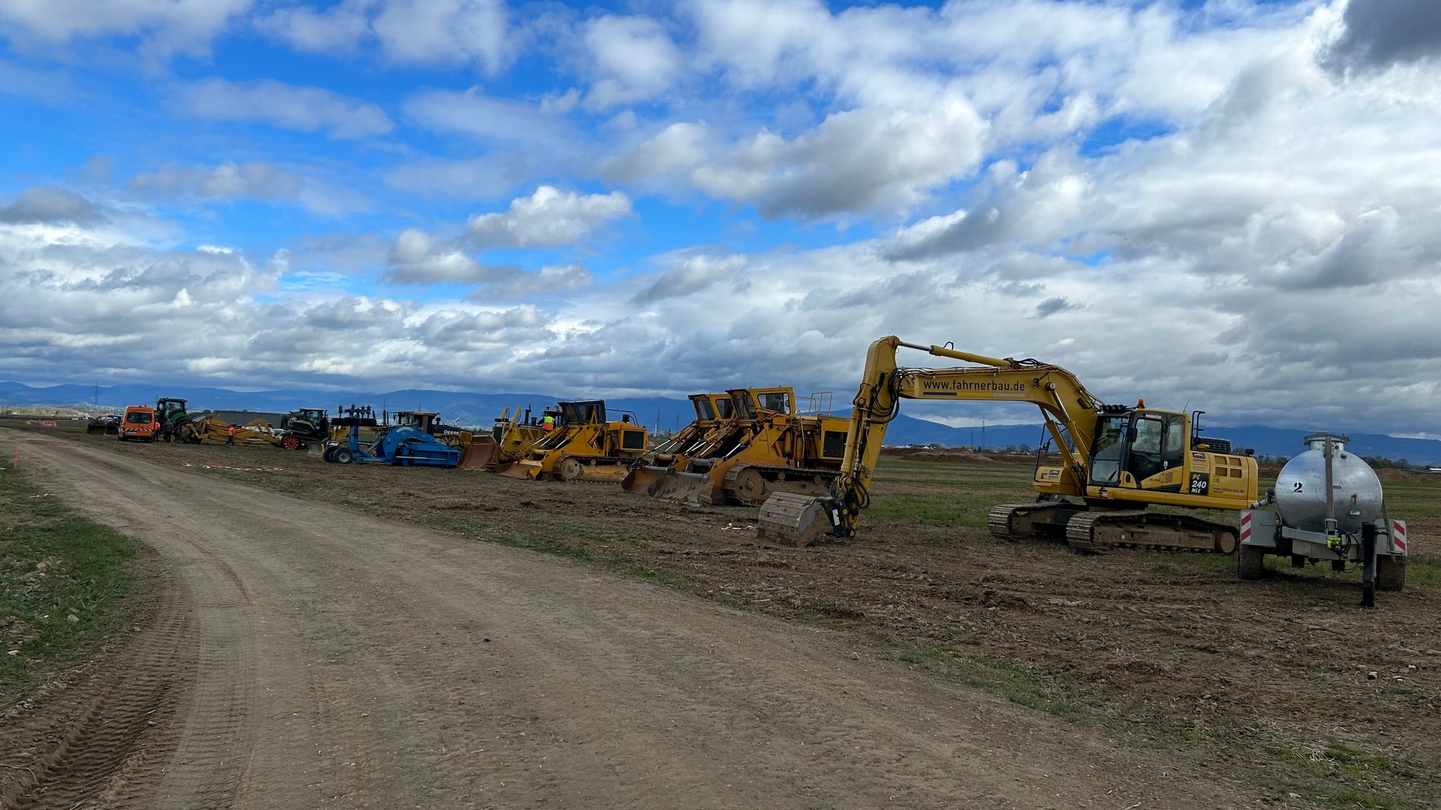 Auf einem Acker im Gäuboden stehen etliche Baumaschinen