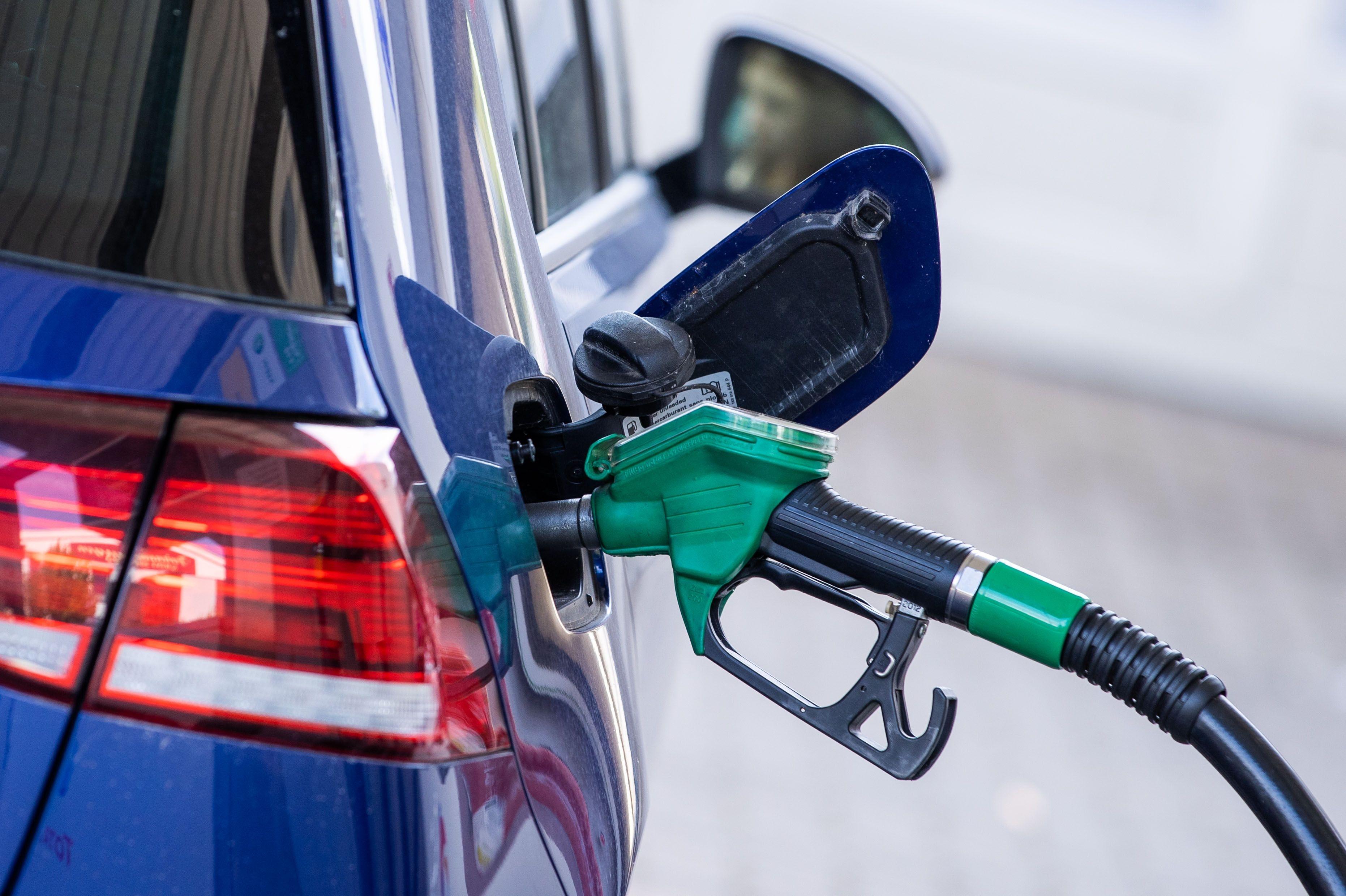  Die Zapfpistole für Super-Kraftstoff steckt in einer Tankstelle im Tankstutzen eines Autos.