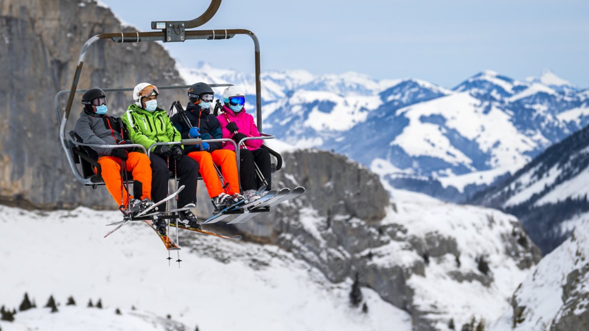 Ein Skiausflug unter Corona-Bedingungen in der Schweiz. Mehrere Menschen sitzen mit Masken in einem Sessellift.