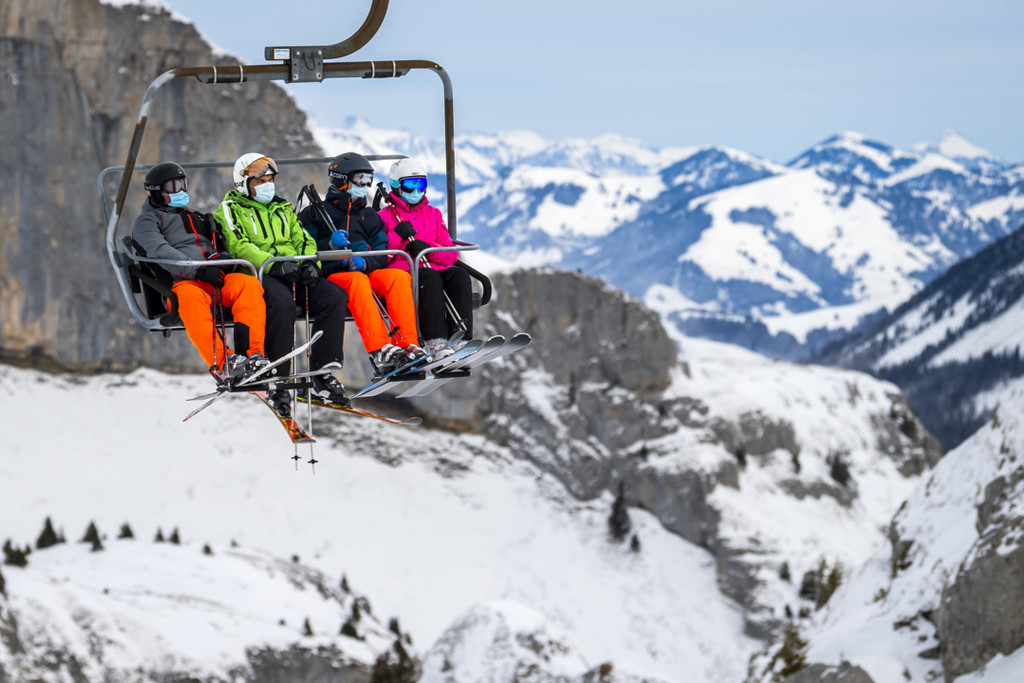 Ein Skiausflug unter Corona-Bedingungen in der Schweiz. Mehrere Menschen sitzen mit Masken in einem Sessellift.