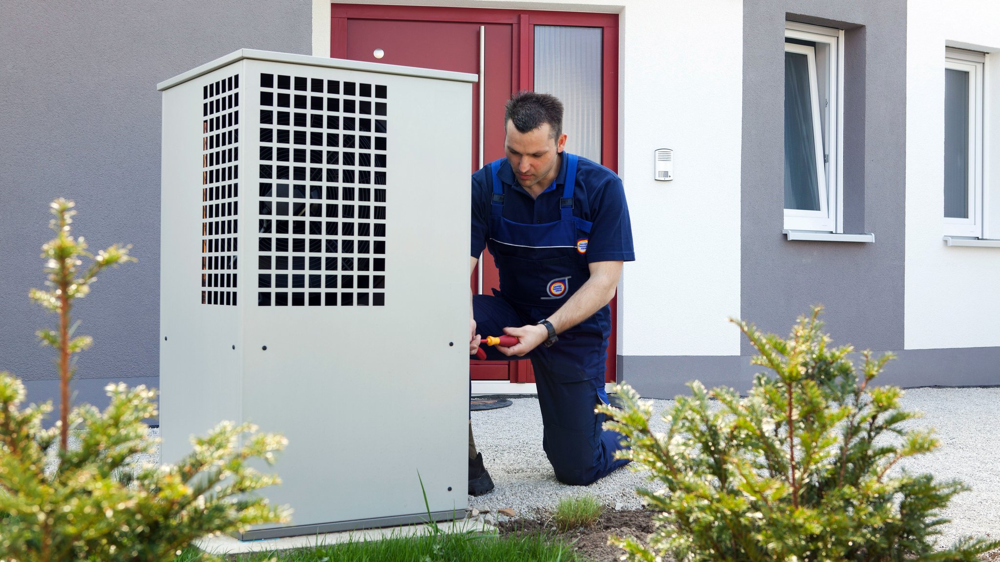 Ein Heizungsmonteur montiert das Gehäuse für eine Wärmepumpe im Rahmen einer Heizungsmodernisierung.