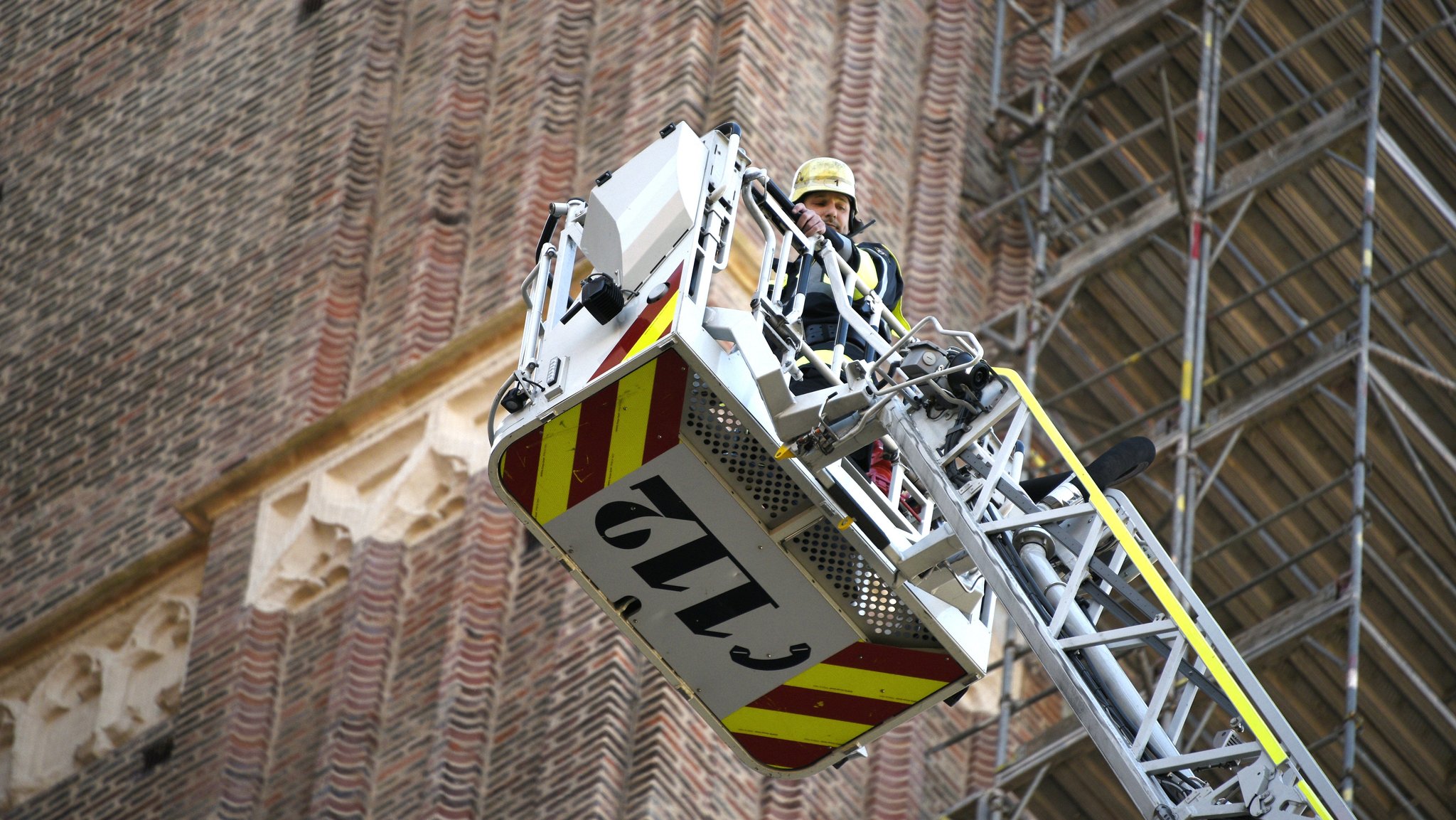 Ein Feuerwehrmann auf einer Hebebühne vor dem Kirchturm der Münchner Frauenkirche.