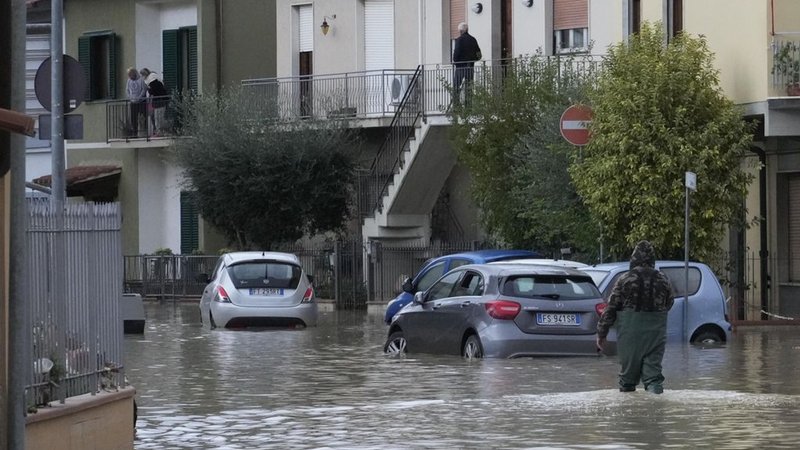 03.11.2023, Italien, Campi di Bisenzio: Ein Mann bahnt sich seinen Weg auf einer überfluteten Straße. Nach den schweren Unwettern mit heftigen Regenfällen in der mittelitalienischen Region Toskana ist die Zahl der Todesopfer gestiegen. Foto: Gregorio Borgia/AP/dpa +++ dpa-Bildfunk +++