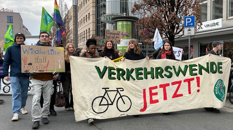Menschen tragen ein Transparent mit der Aufschrift "Verkehrswende jetzt" durch Nürnberg. | Bild:BR24/Tina Wenzel