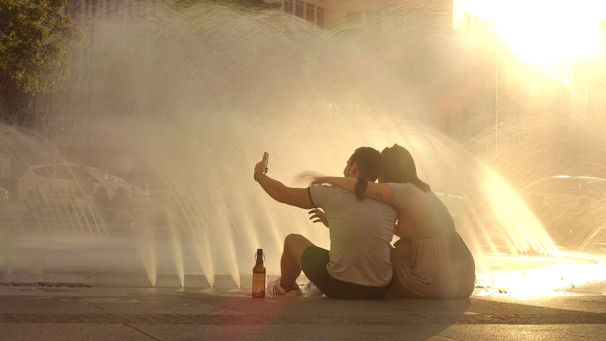 Zwei Menschen kühlen sich am Stachus-Brunnen in München ab.