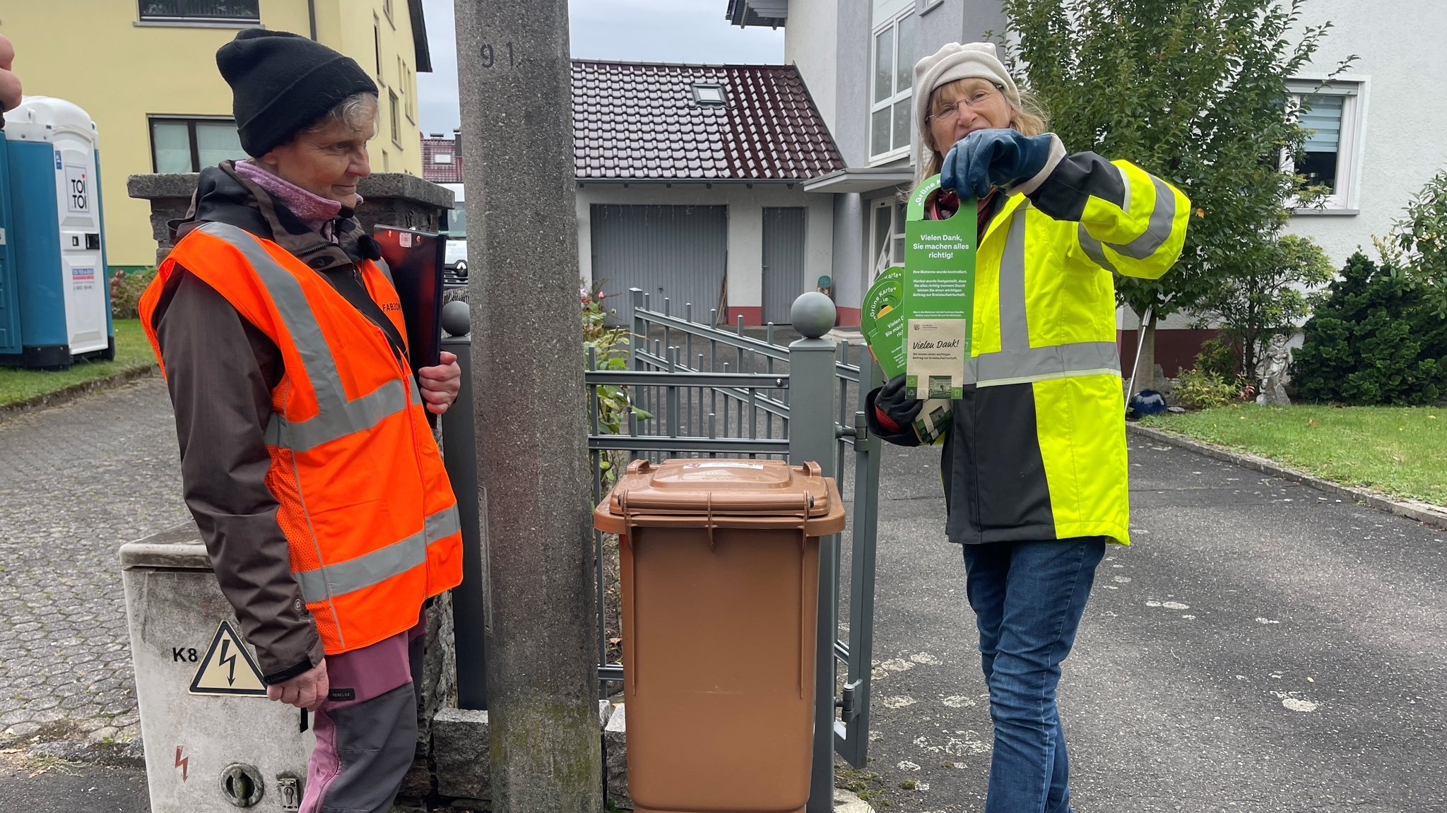 Eva Berthold und Petra Hoeß vom Umweltbüro Fabion markieren die Biomülltonne mit einem grünen Aufhänger.
