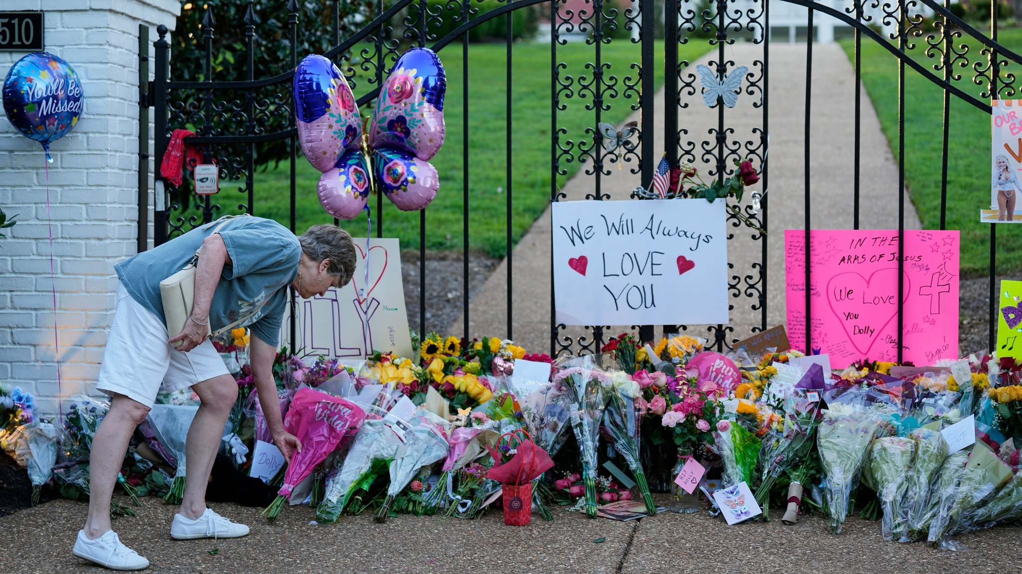 25.08.2026, USA, Brentwood: Becky Wangner legt Blumen an einer provisorischen Gedenkstätte zu Ehren von Dolly Parton vor deren Haus nieder. Foto: George Walker IV/AP/dpa +++ dpa-Bildfunk +++ | Bild: dpa-Bildfunk/George Walker IV 25.08.2026, USA, Brentwood: Becky Wangner legt Blumen an einer provisorischen Gedenkstätte zu Ehren von Dolly Parton vor deren Haus nieder. Foto: George Walker IV/AP/dpa +++ dpa-Bildfunk +++