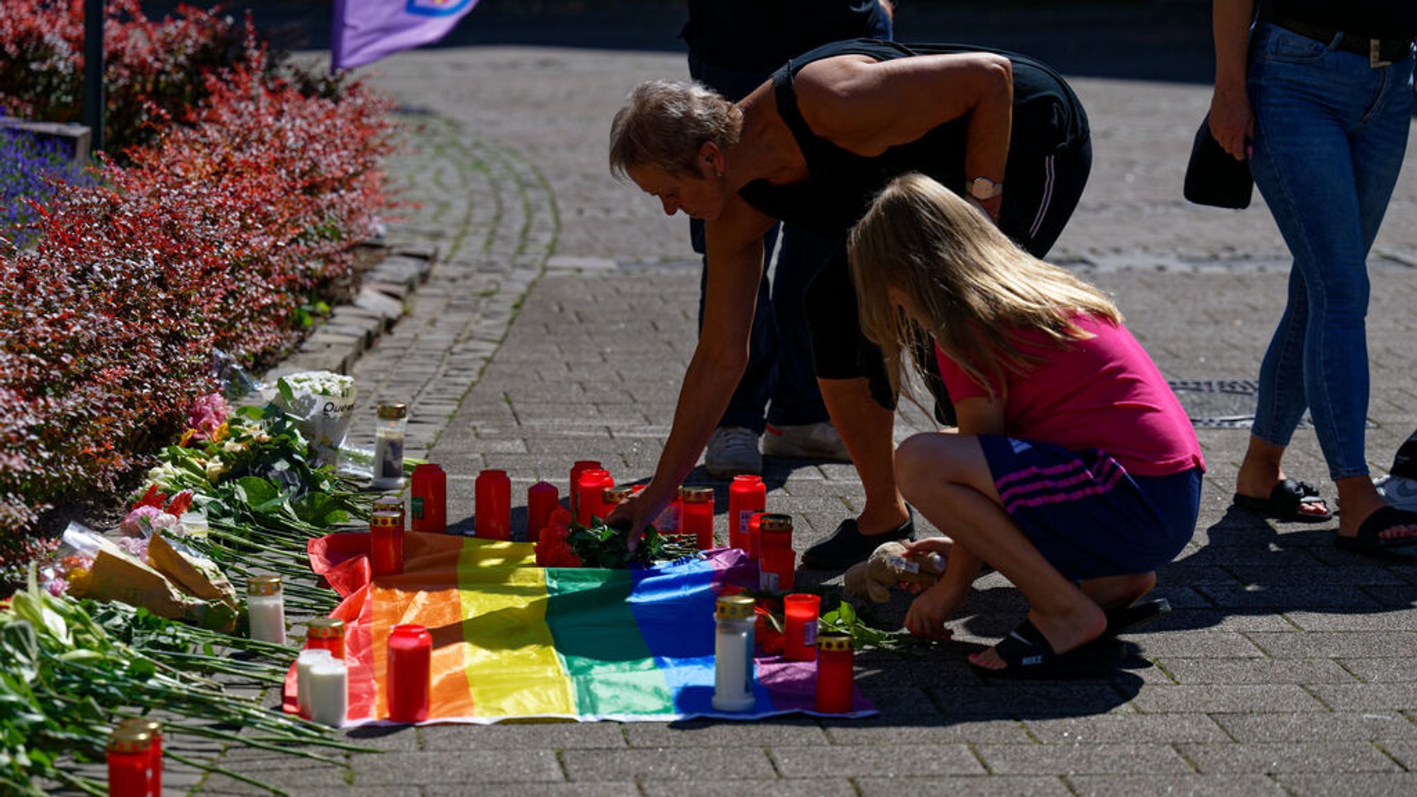 24.08.2024, Nordrhein-Westfalen, Solingen: Nach der Messerattacke auf dem Solinger Stadtfest legen Menschen in der Nähe des Tatortes Blumen neben einer Regenbogenflagge nieder. Bei einer Attacke auf der 650-Jahr-Feier der Stadt Solingen hat es Todesopfer und Verletzte gegeben. Foto: Henning Kaiser/dpa - ACHTUNG: Nur zur redaktionellen Verwendung im Zusammenhang mit der aktuellen Berichterstattung. Das Foto darf nicht verändert und nur im vollen Ausschnitt verwendet werden. +++ dpa-Bildfunk +++