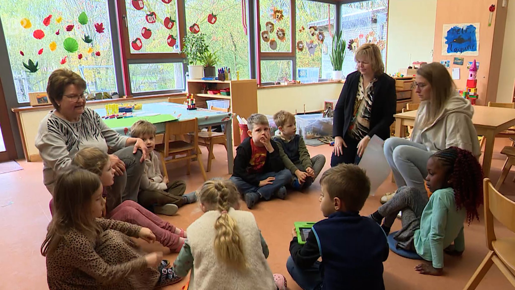 Kinder und Betreuerinnen sitzen gemeinsam in der Kinderkonferenz.