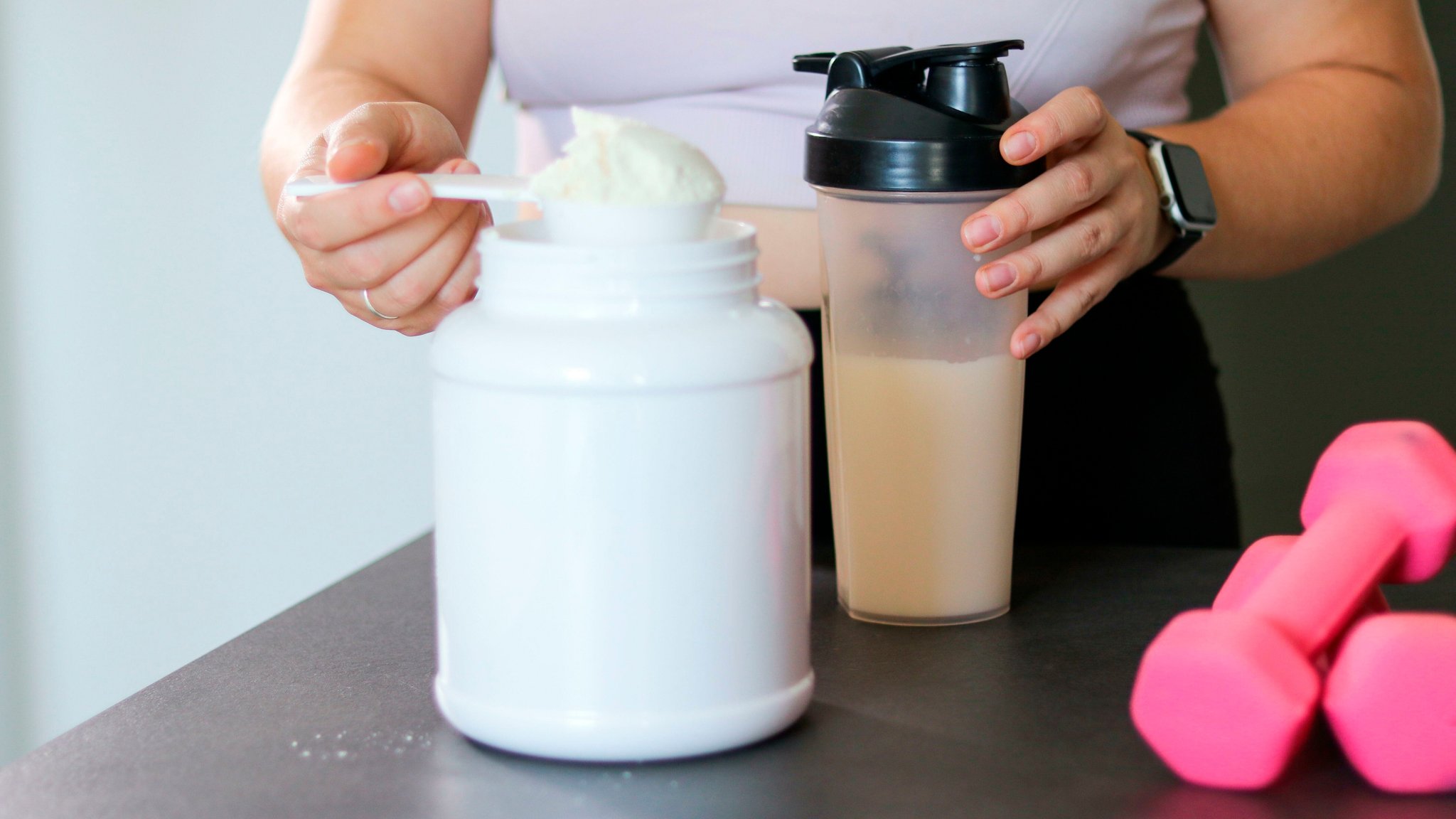 Eine Hand misst Proteinpulver ab