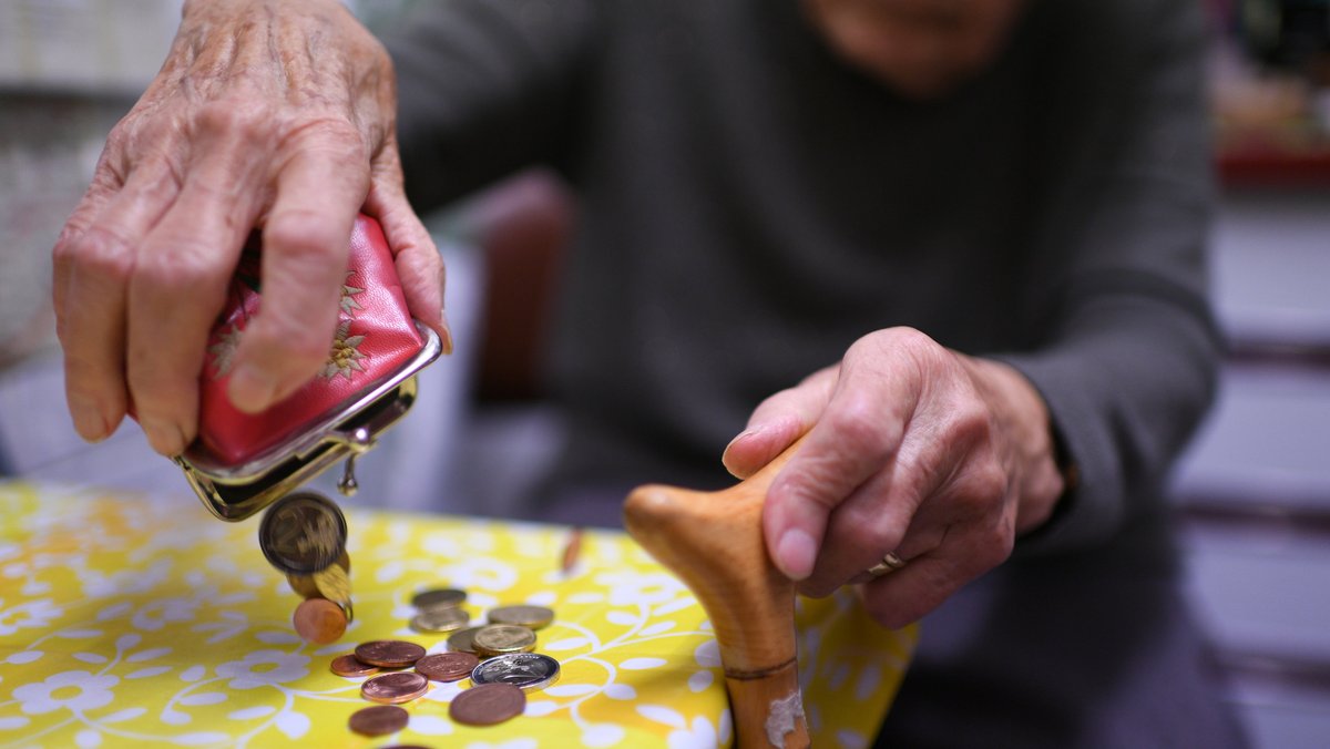 Symbolbild: Eine Rentnerin schüttet den Inhalt ihres Geldbeutels auf den Küchentisch.