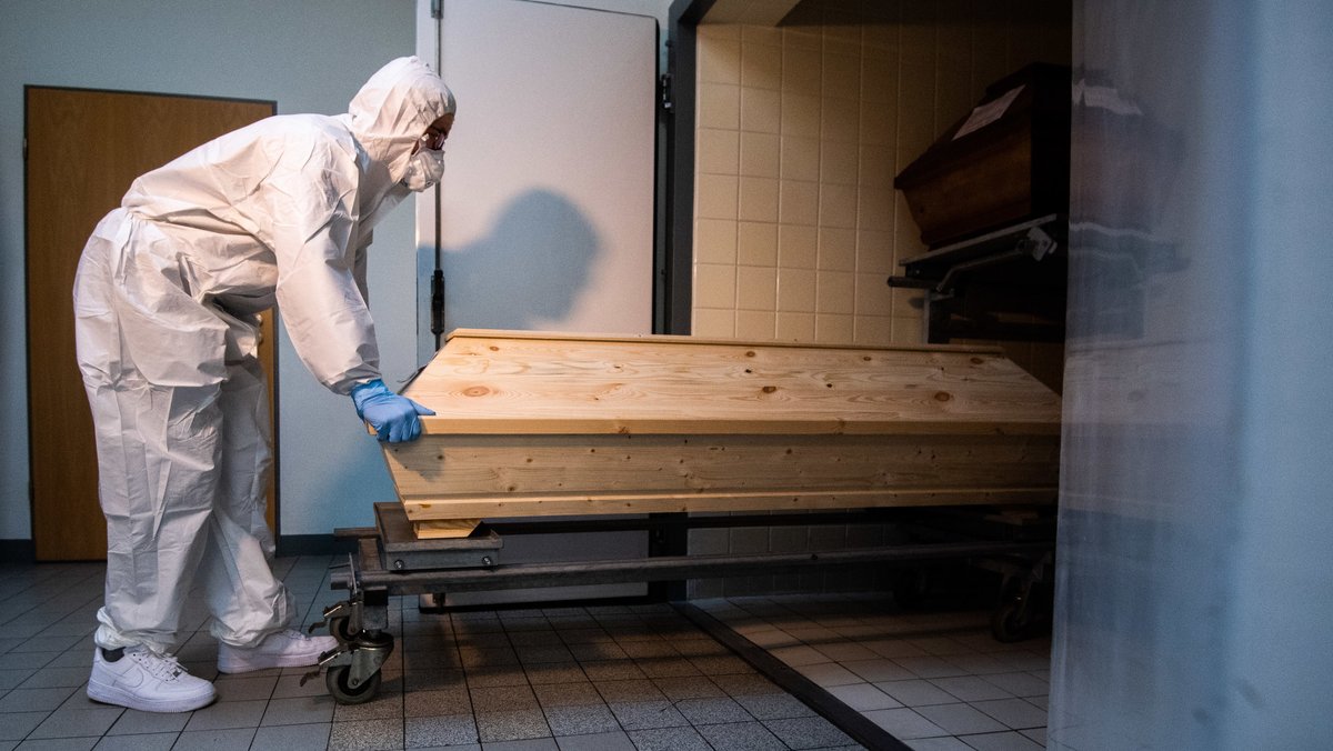 Ein Mitarbeiter schiebt in einem Krematorium einen Sarg in eine Kühlkammer, in der Särge von Verstorbenen stehen, die mit oder an dem Corona-Virus gestorben sind.