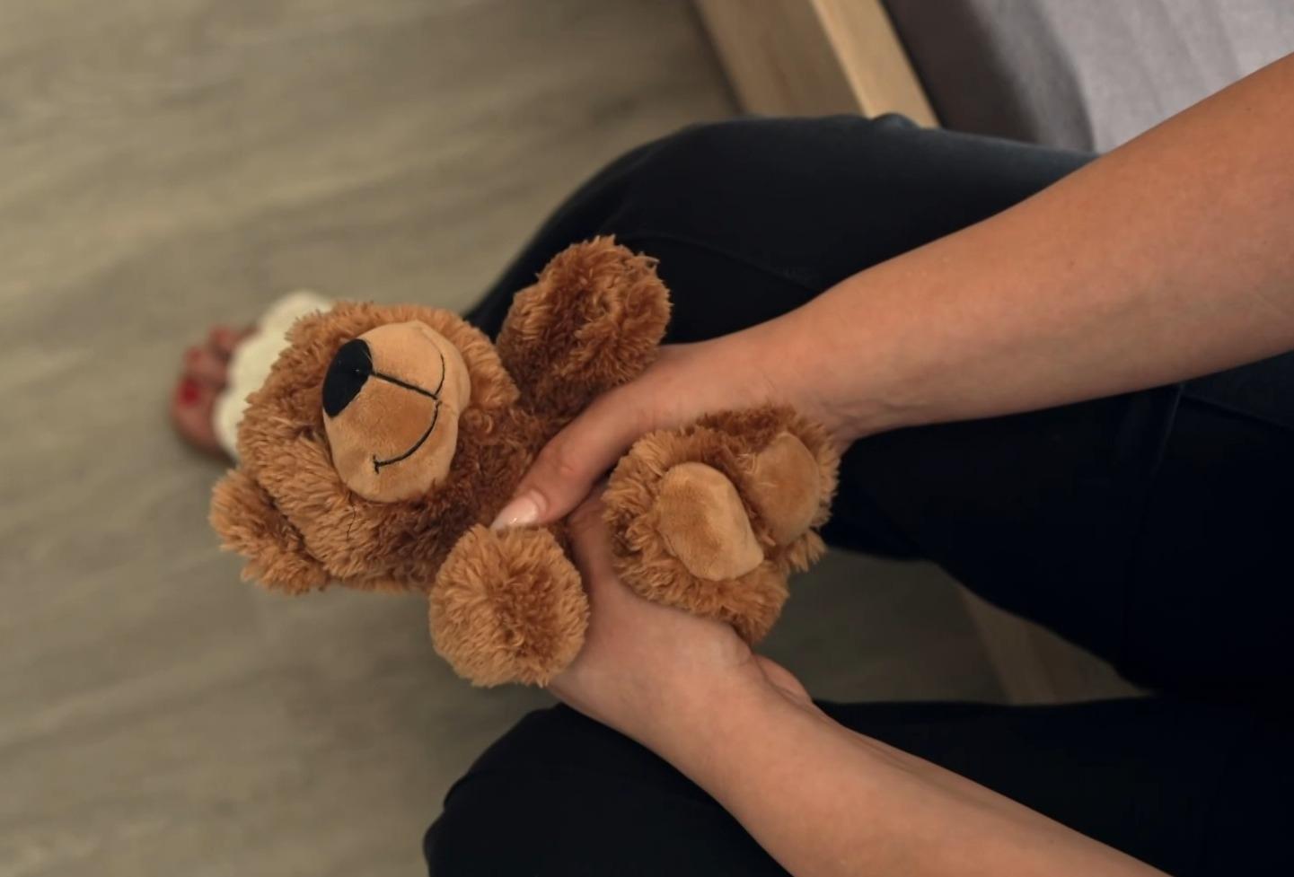 Eine Frau hält einen Kuschel-Teddy.