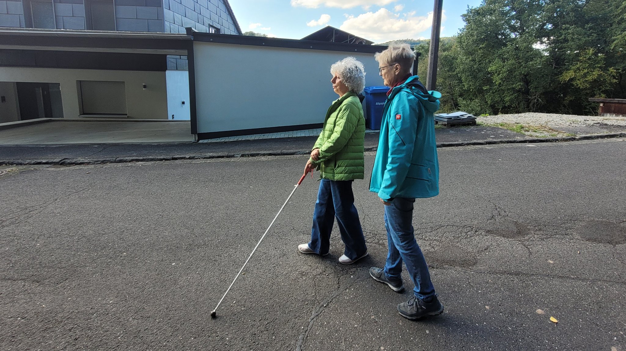 Eine Frau geht am Blindenstock, hinter ihr läuft ihre Mobilitätstrainerin.
