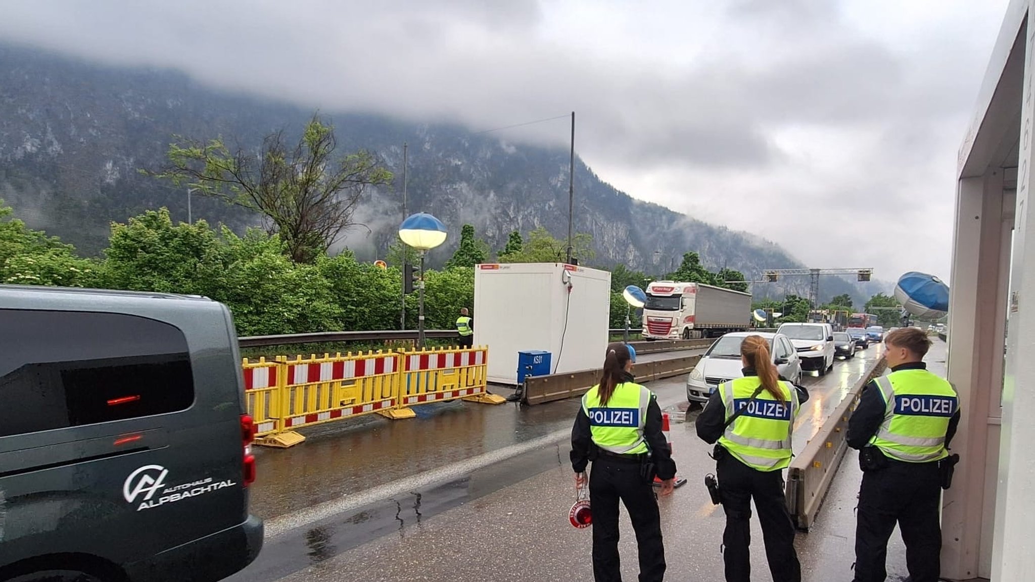 Drei Bundespolizisten inspizieren passierende Autos an einem Grenzübergang