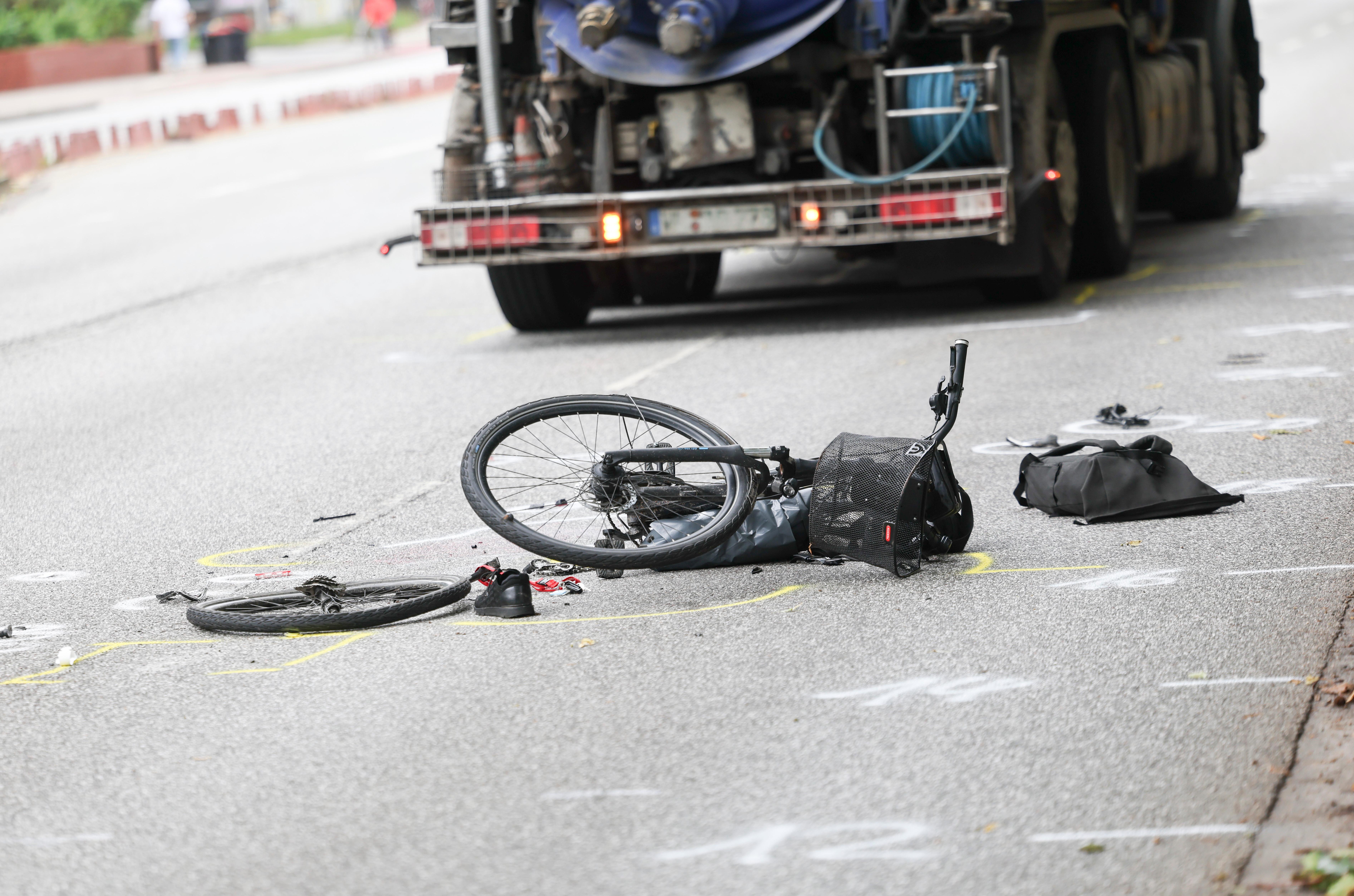 Symbolbild: Zerstörtes Fahrrad liegt auf der Straße, dahinter ein Lkw