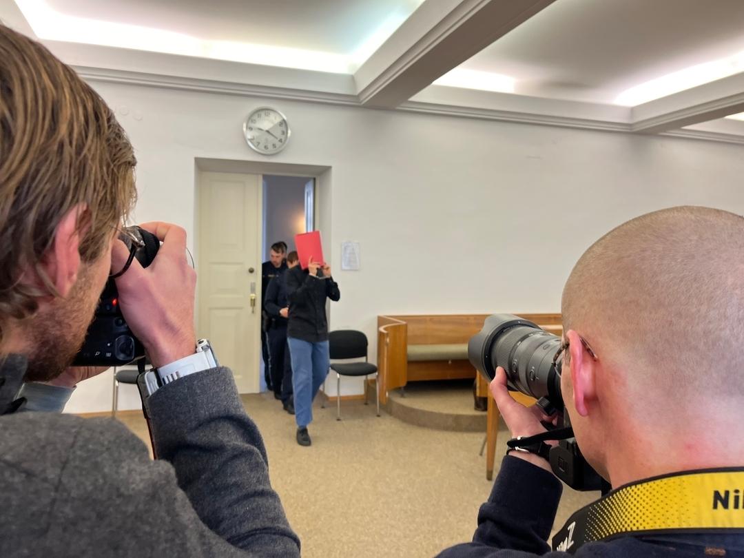 Der Angeklagte betritt mit einer Mappe vor dem Gesicht den Gerichtssaal-