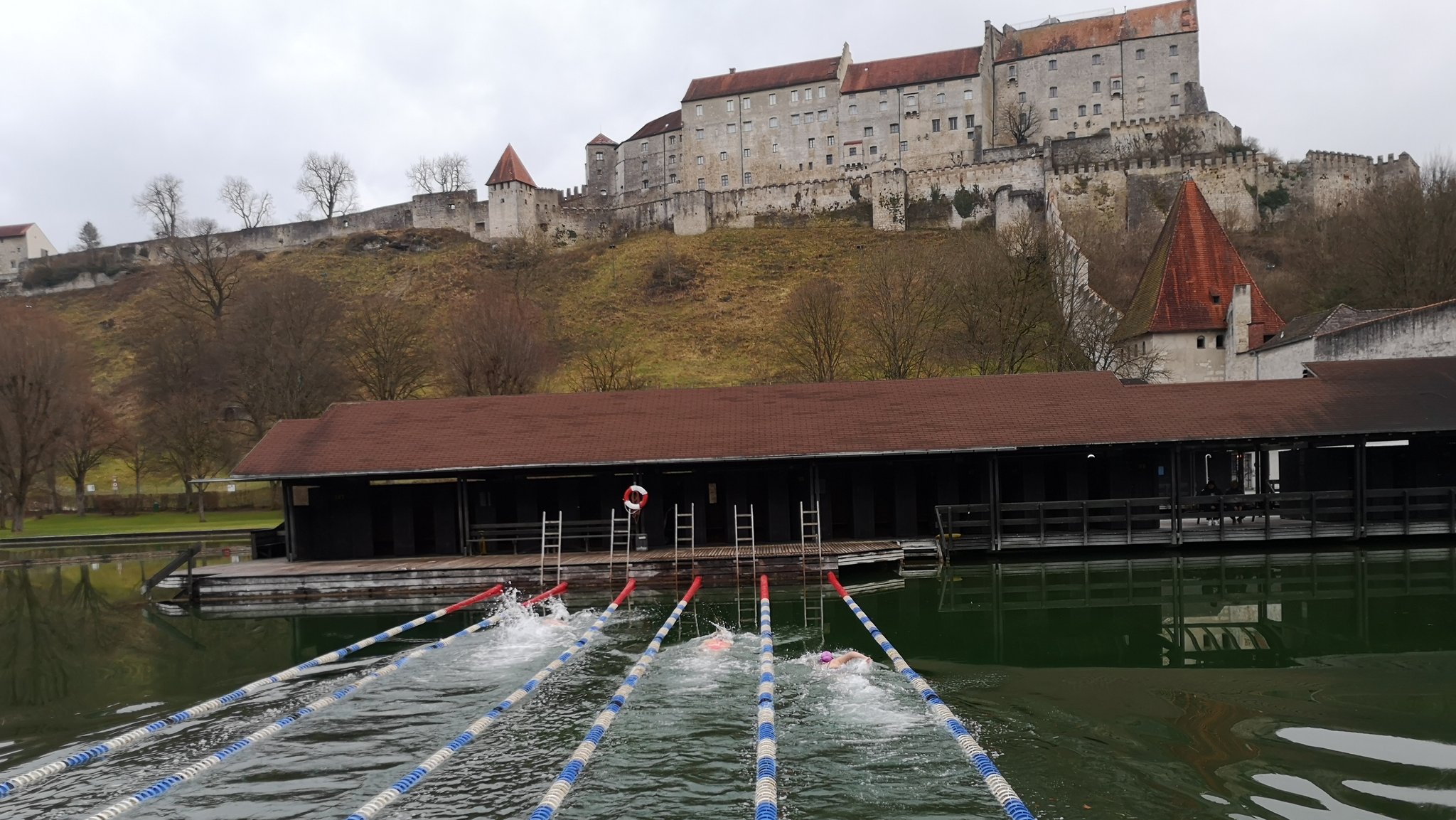 Eisschwimmarena im Wöhrsee vor historischer Burgkulisse.