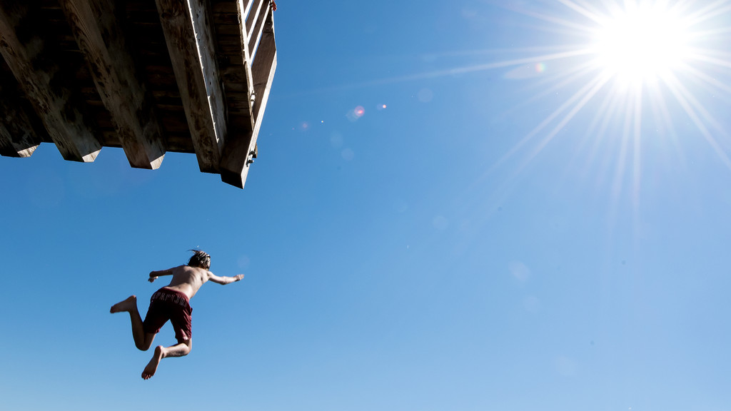 Ein Bub springt vom Sprungturm eines Freibades (Symbolbild)