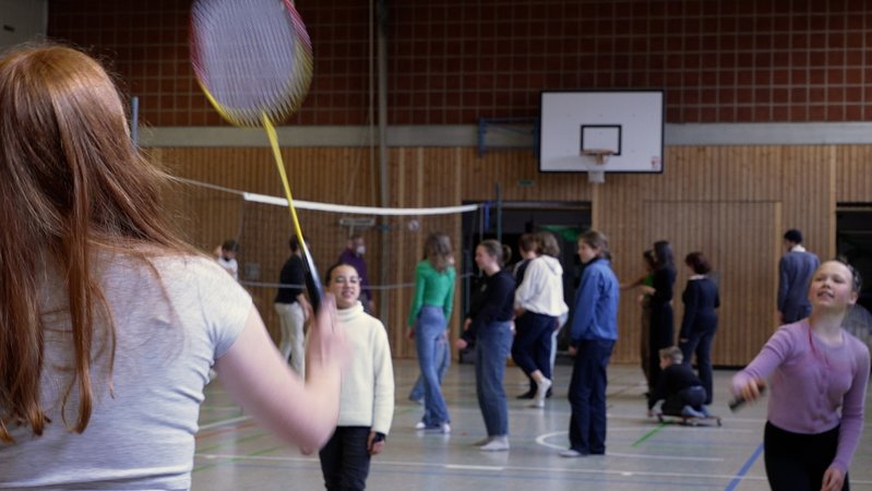 Blick in die Turnhalle des Ignaz-Günther-Gymnasiums in Rosenheim. Kinder und Jugendliche spielen unter anderem Federball und Volleyball.