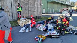 Geschminkte Statisten liegen als Verletze in Aludecken gehüllt am Boden und werden von Feuerwehrkräften versorgt.  | Bild:ILS/Bernhard Schwarz