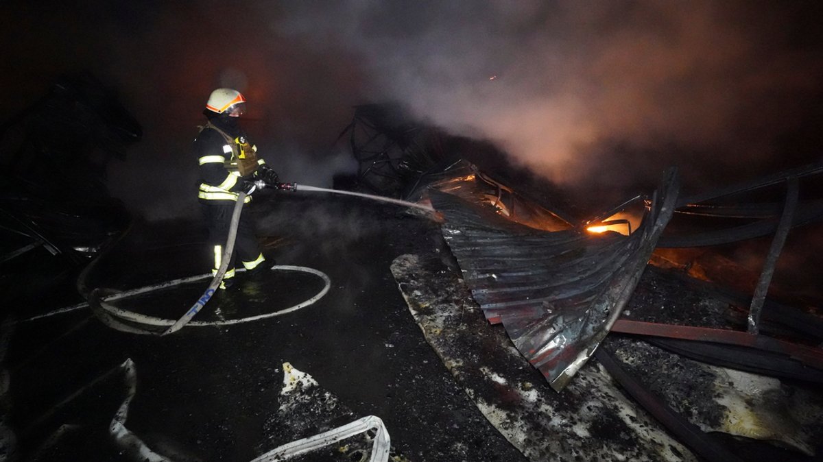 Feuerwehrleute löschen das Feuer nach einem Treffer durch russischen Granatenbeschuss in Charkiw, Ukraine.