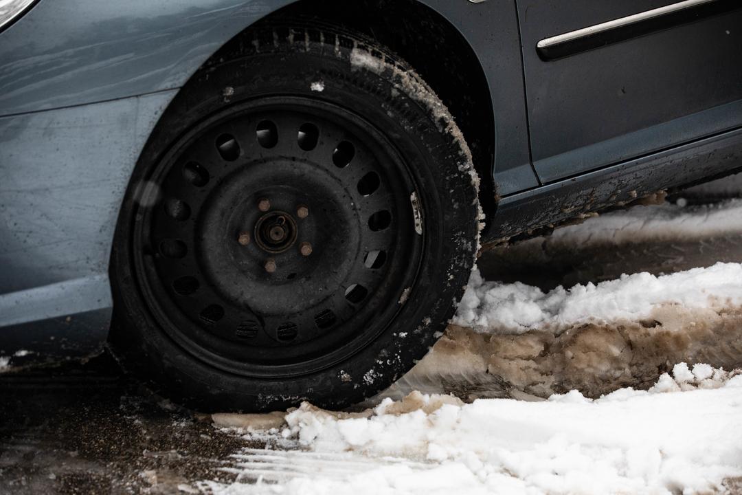 Ein Auto mit Winterreifen fährt durch den Schneematsch.