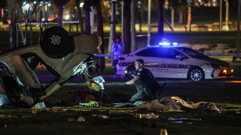 07.04.2023, Israel, Tel Aviv: Polizisten und Forensiker arbeiten neben einem Auto nach einem Anschlag