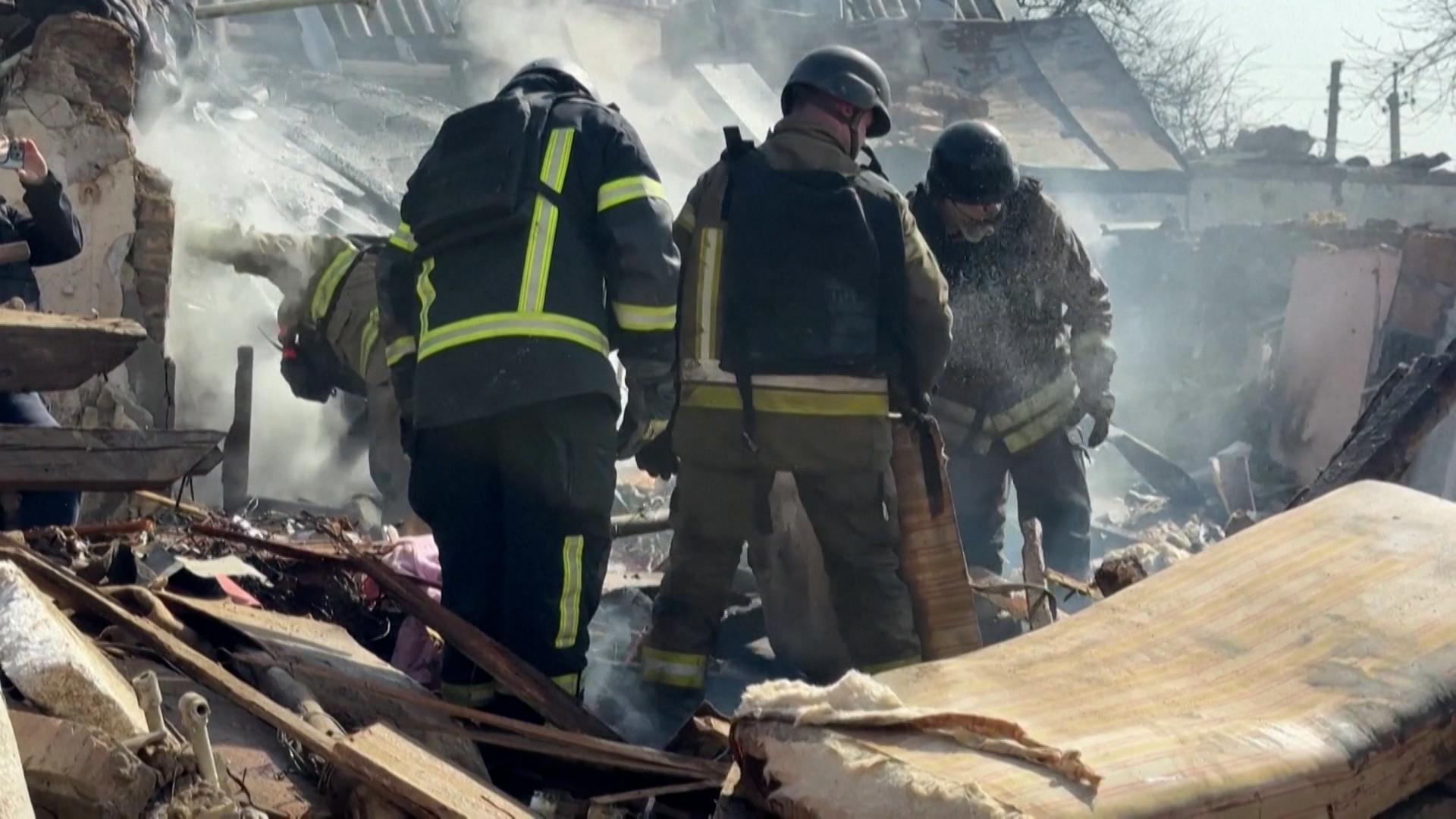 Männer durchsuchen zerstörte Gebäude