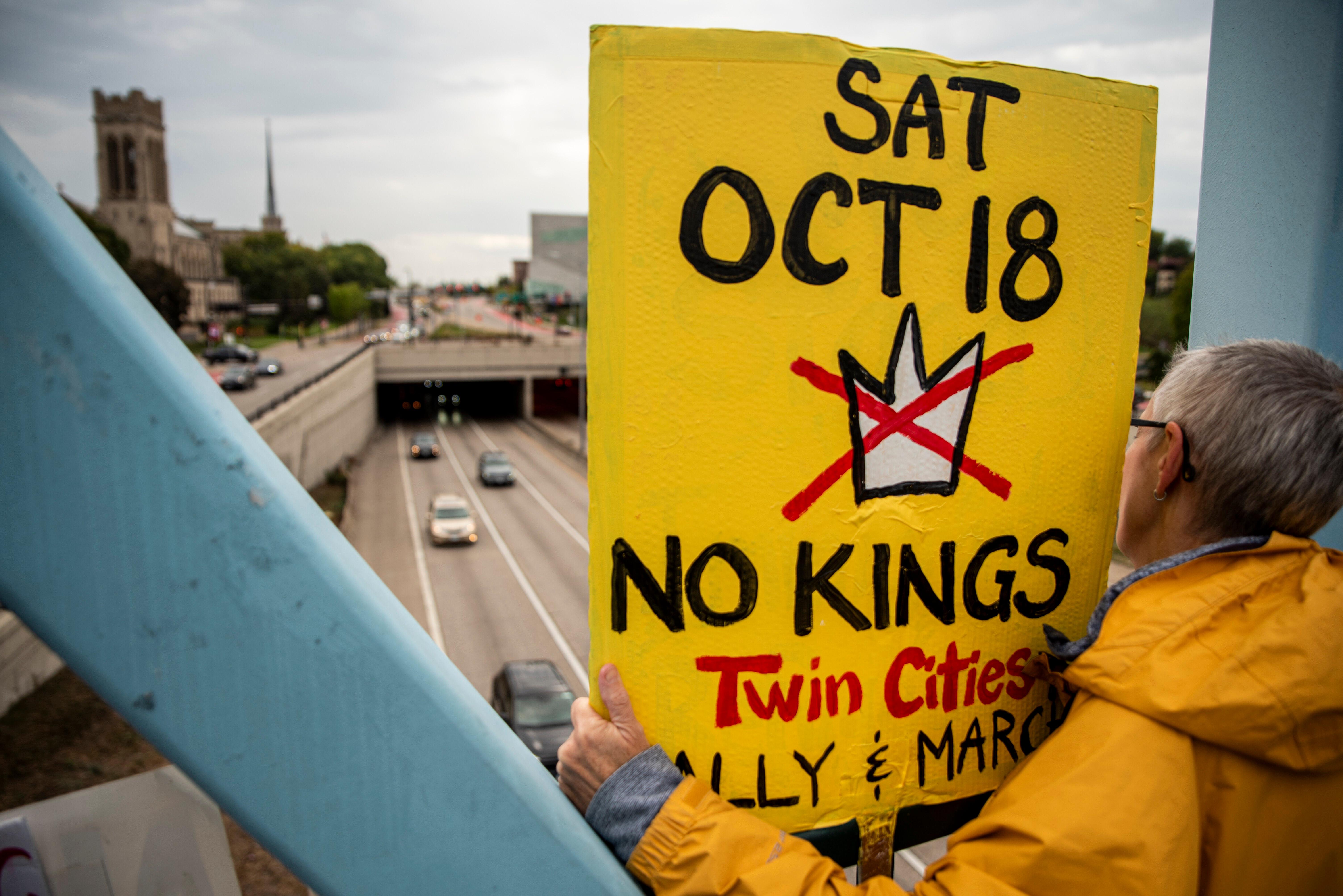 Ein Mann hält ein Plakat, das auf die geplanten Anti-Trump-Proteste hinweist, auf eienr Brücke in die Höhe, um die Kundgebungen zu bewerben