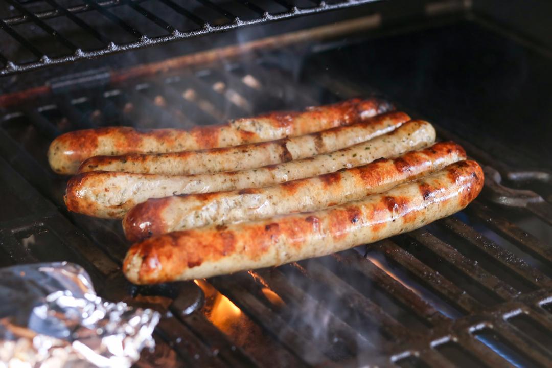 Bratwürste liegen auf einem Grill. 