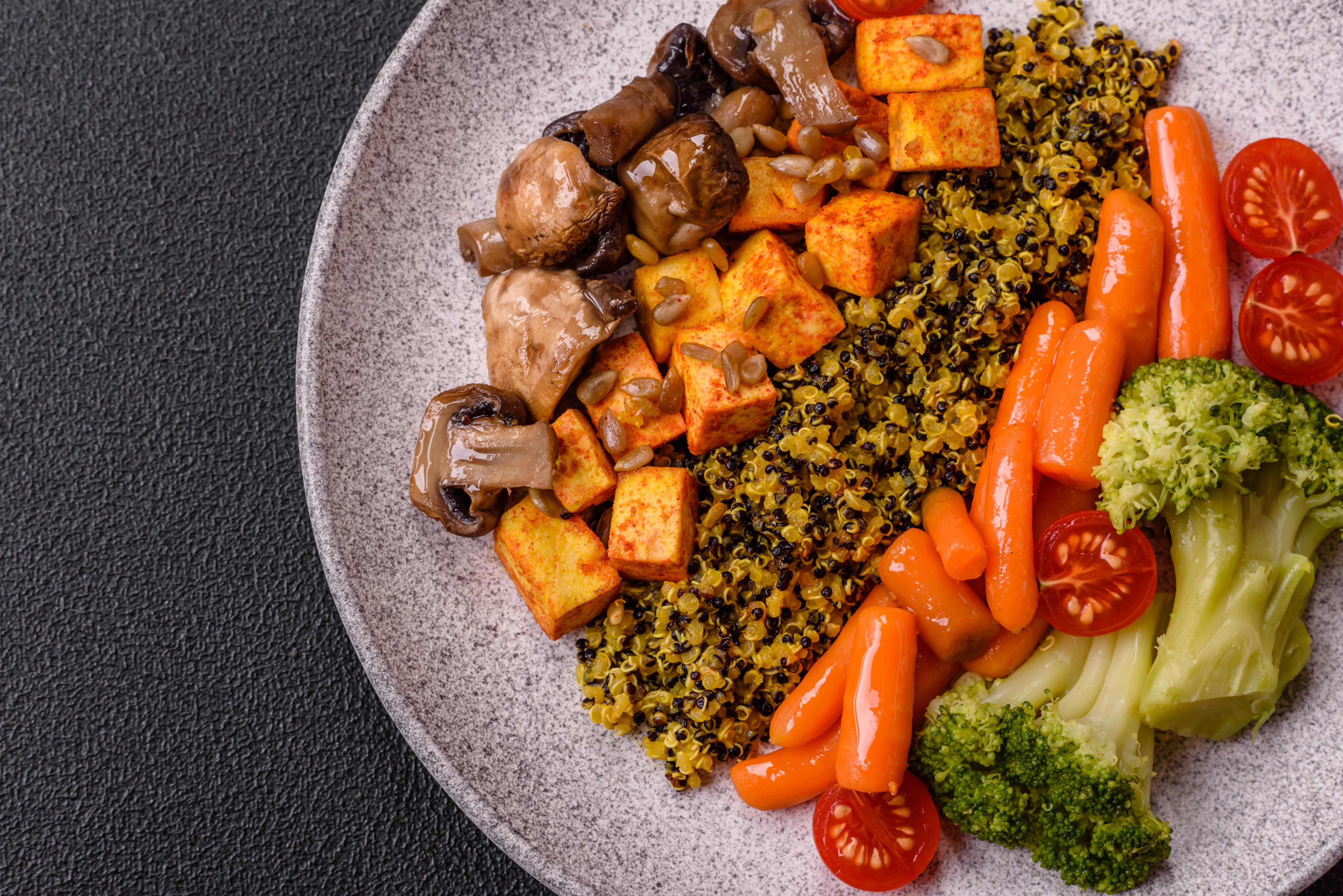 Ein Teller mit vegetarischen Lebensmitteln wie Tofu, Pilzen, Karotten etc. von oben