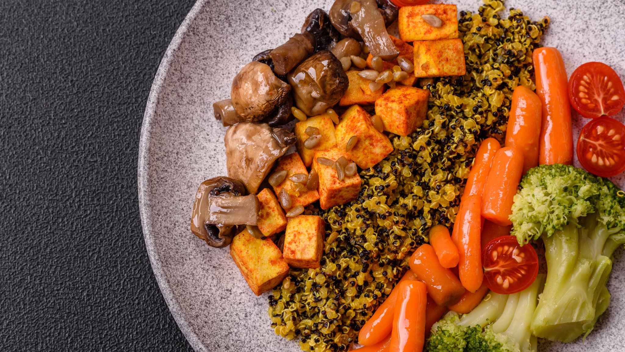 Ein Teller mit vegetarischen Lebensmitteln wie Tofu, Pilzen, Karotten etc. von oben