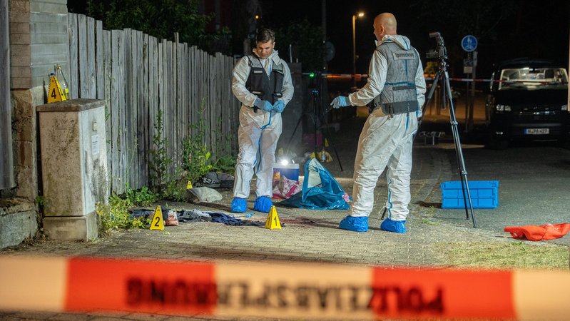 Zwei Männer der Spurensicherung stehen in Overall, Westen und blauen Überzügen über den Schuhen am Tatort, der mit Polizeiband abgesperrt und mit kleinen gelben Markierungen versehen ist. Bei einer Auseinandersetzung in der Nähe des Brombachsees ist ein 15-Jähriger erstochen worden. | Bild: News5 / Ferdinand Merzbach Zwei Männer der Spurensicherung stehen in Overall, Westen und blauen Überzügen über den Schuhen am Tatort, der mit Polizeiband abgesperrt und mit kleinen gelben Markierungen versehen ist. Bei einer Auseinandersetzung in der Nähe des Brombachsees ist ein 15-Jähriger erstochen worden.