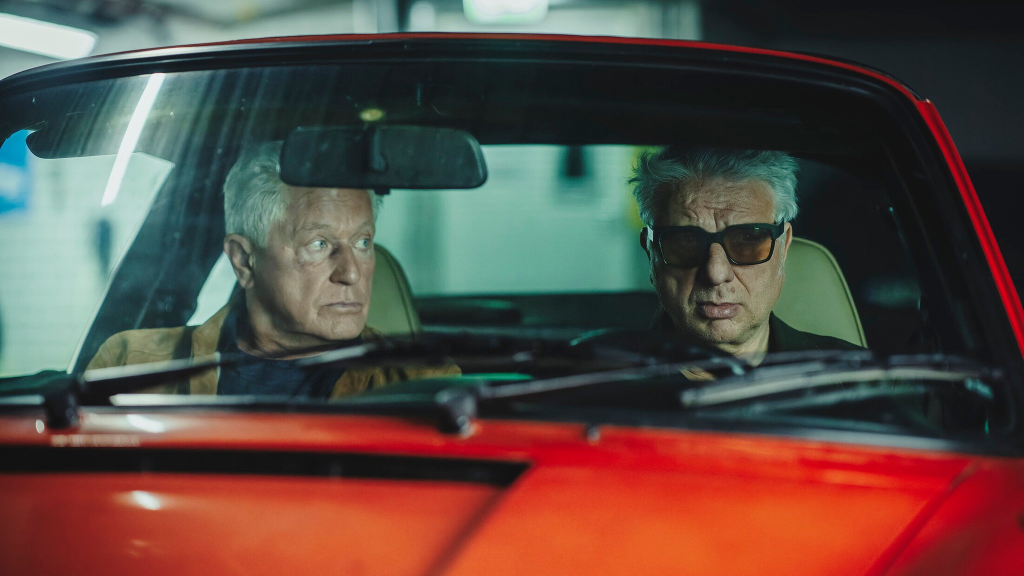 Kriminalhauptkommissar Ivo Batic (Miroslav Nemec) und Kriminalhauptkommissar Franz Leitmayr (Udo Wachtveitl) sitzen im Porsche in der Tiefgarage und beobachten die Mitarbeiter von Prime Wave.